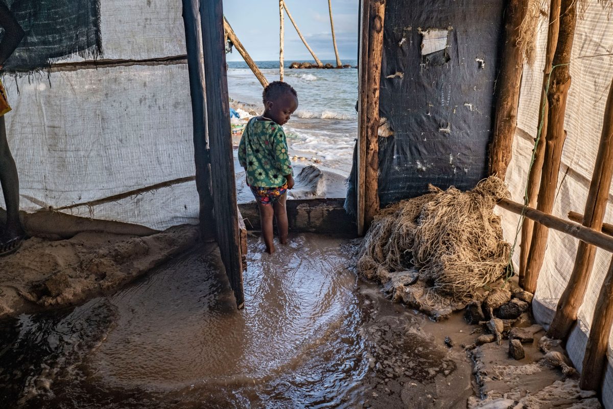 A boy looks on as seawater floods into his home.