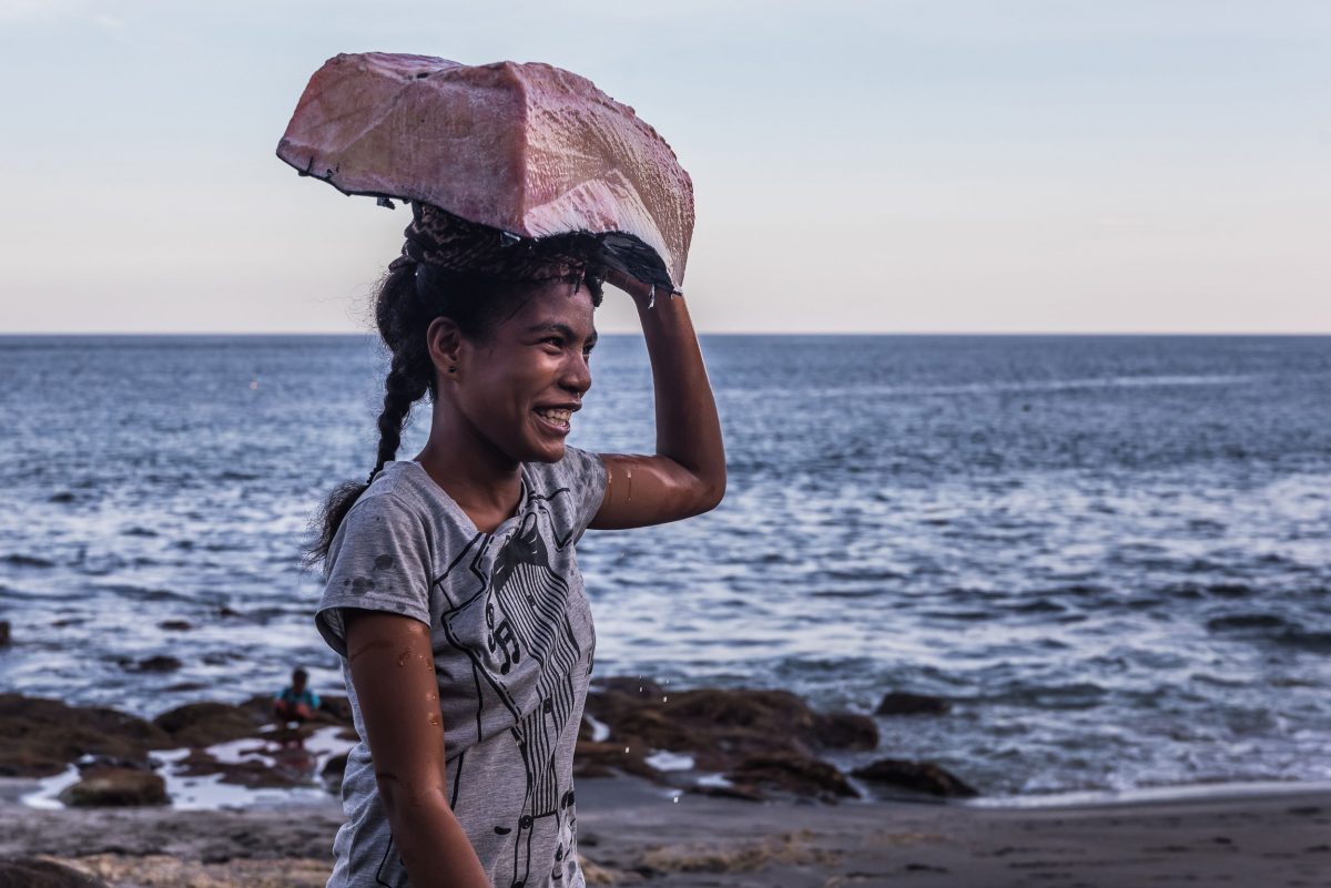 an Indonesian woman carries whale meat on her head
