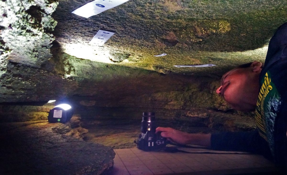 Charles Helm photographs the footprints his team found in a South African coastal cave. Photo by Guy Thesen