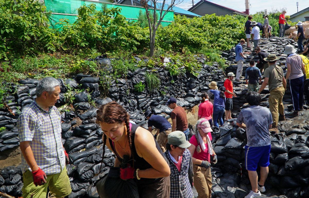 On Rebun Island, off the coast of Hokkaido, Hirofumi Kato, left, Zoe Eddy, foreground, and volunteers pile sandbags on the Hamanaka II archaeological site, where they will stay until the dig continues the following year. Photo by Jude Isabella