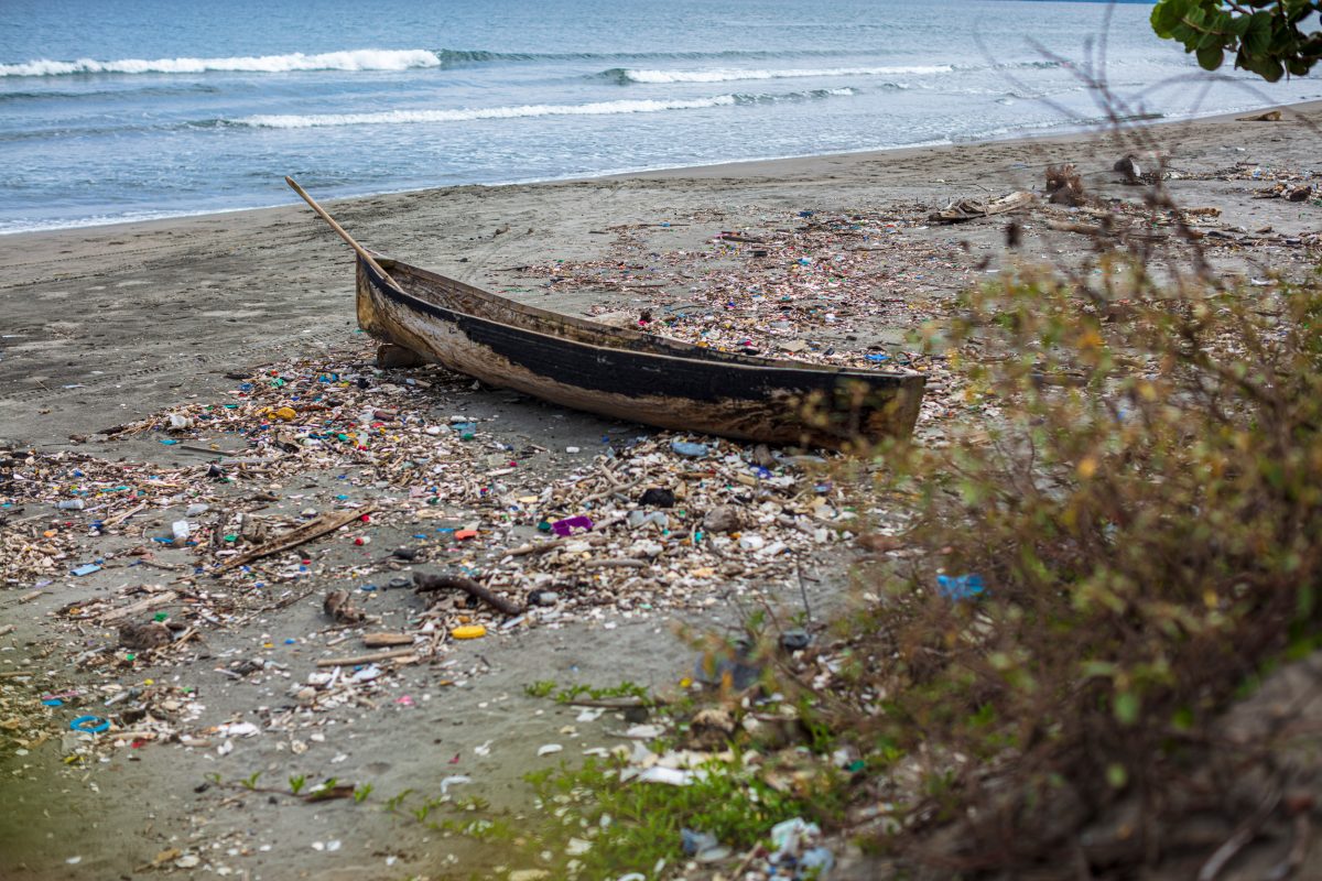 boat on beach surrounded by garbage