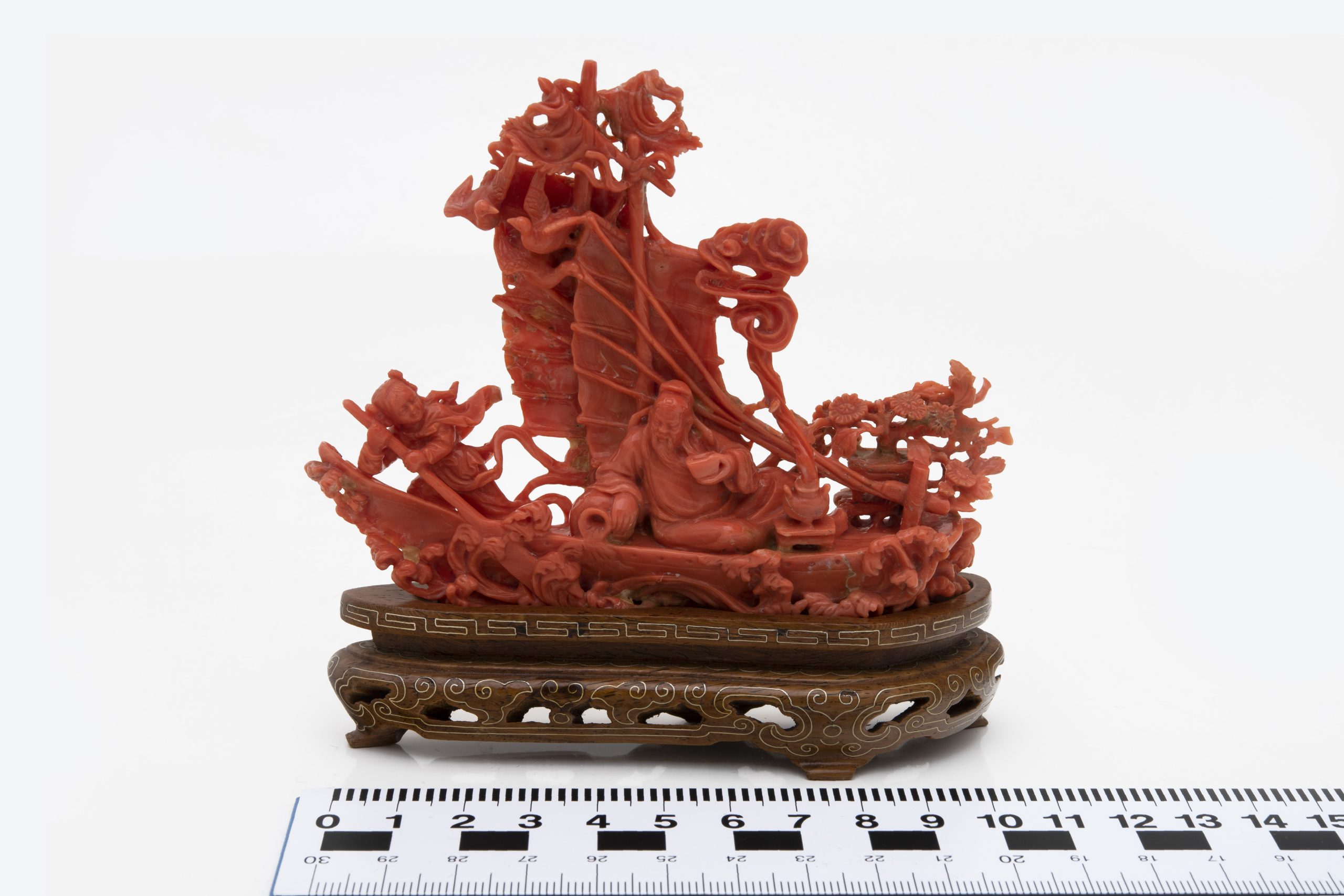 A carved red coral boat done in an intricate asian style.