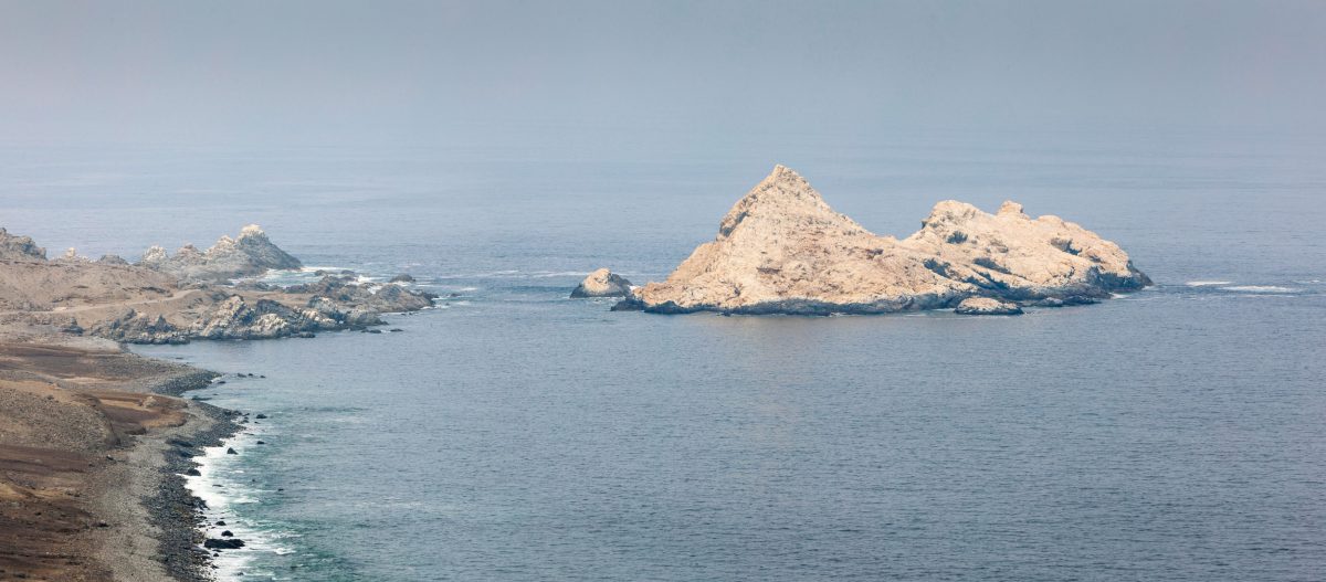 Rocky coast of northern Chile with bird island covered with guano