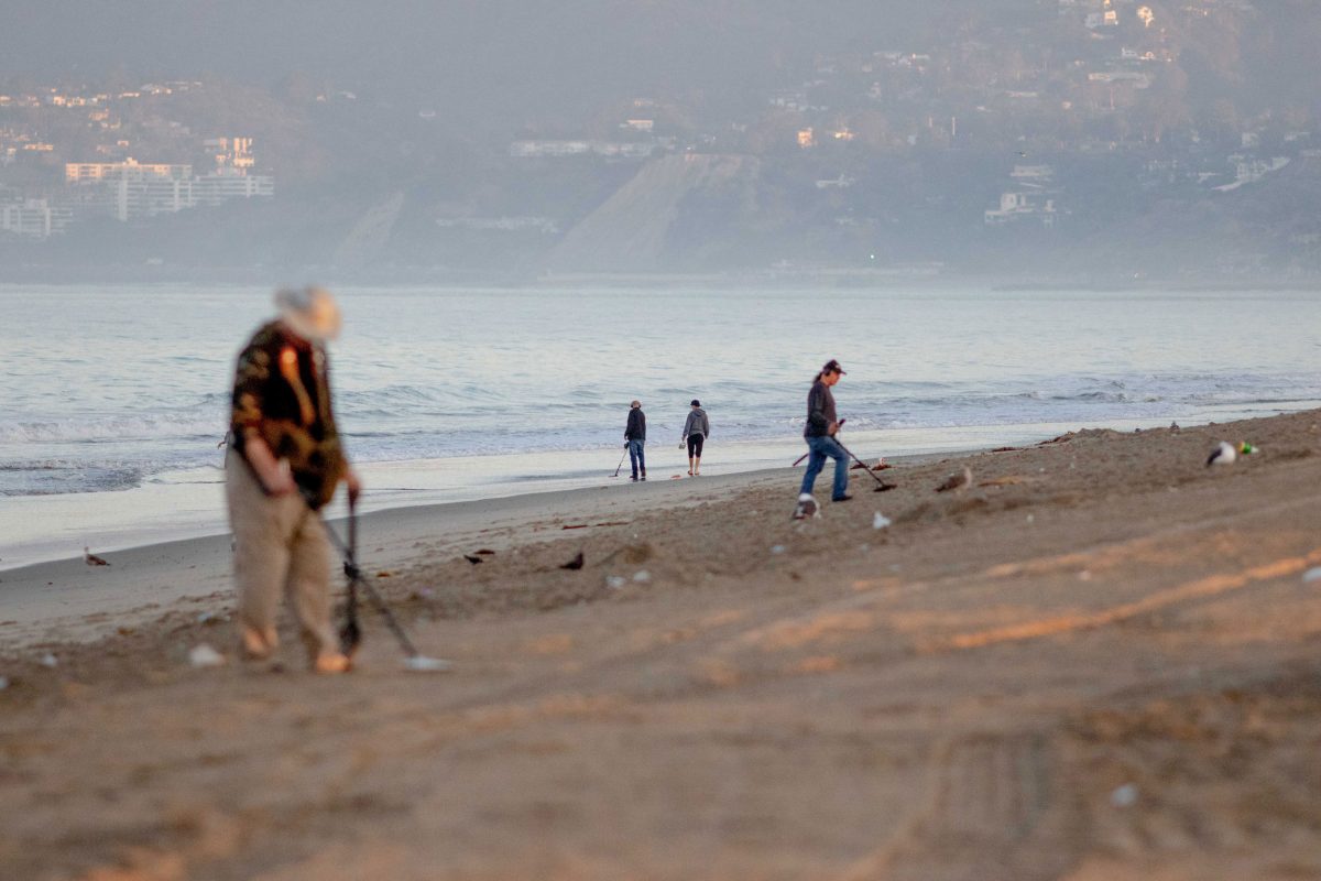 metal detectorists on Santa Monica Beach at sunrise