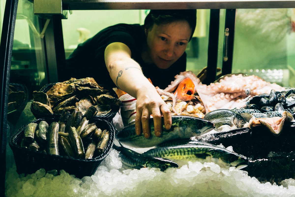 Fiona Lewis reaches for a fish in a display case at her shop, The District Fishwife. Photo courtesy of Fiona Lewis