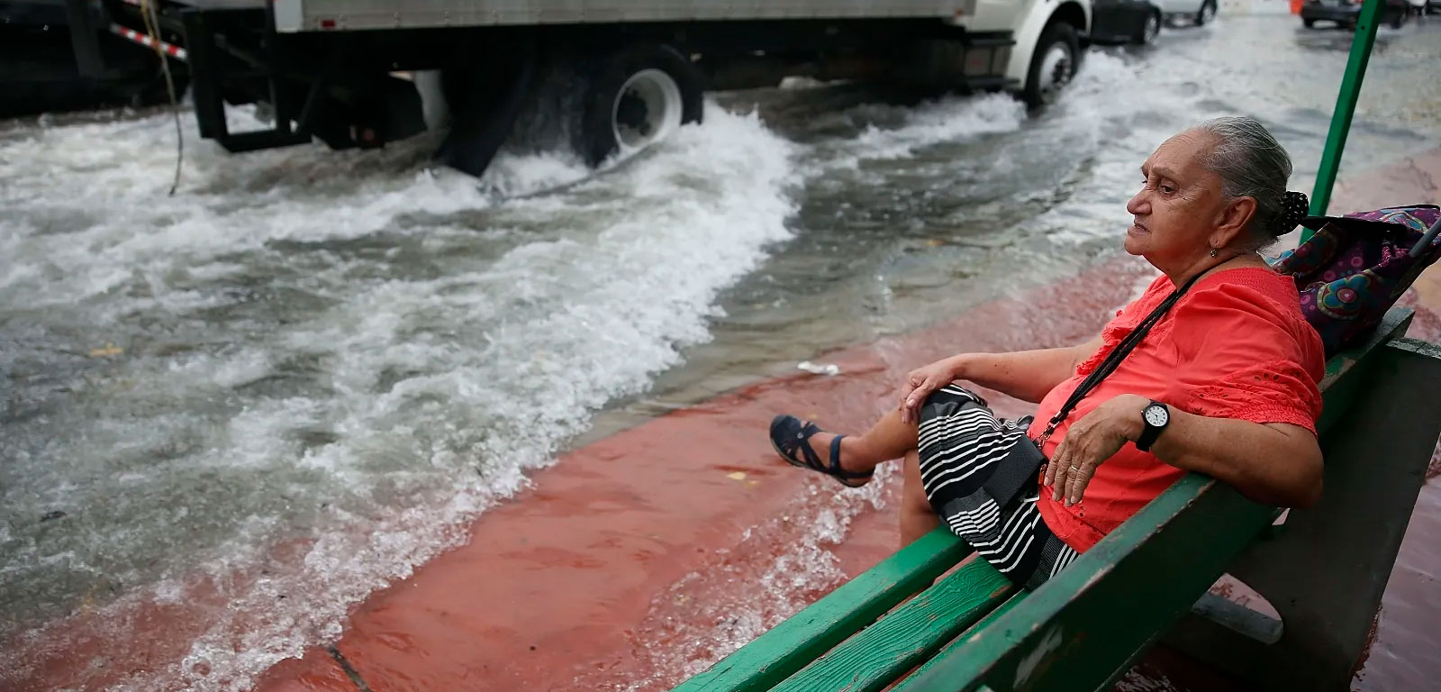 woman sitting on bench next to flooded street