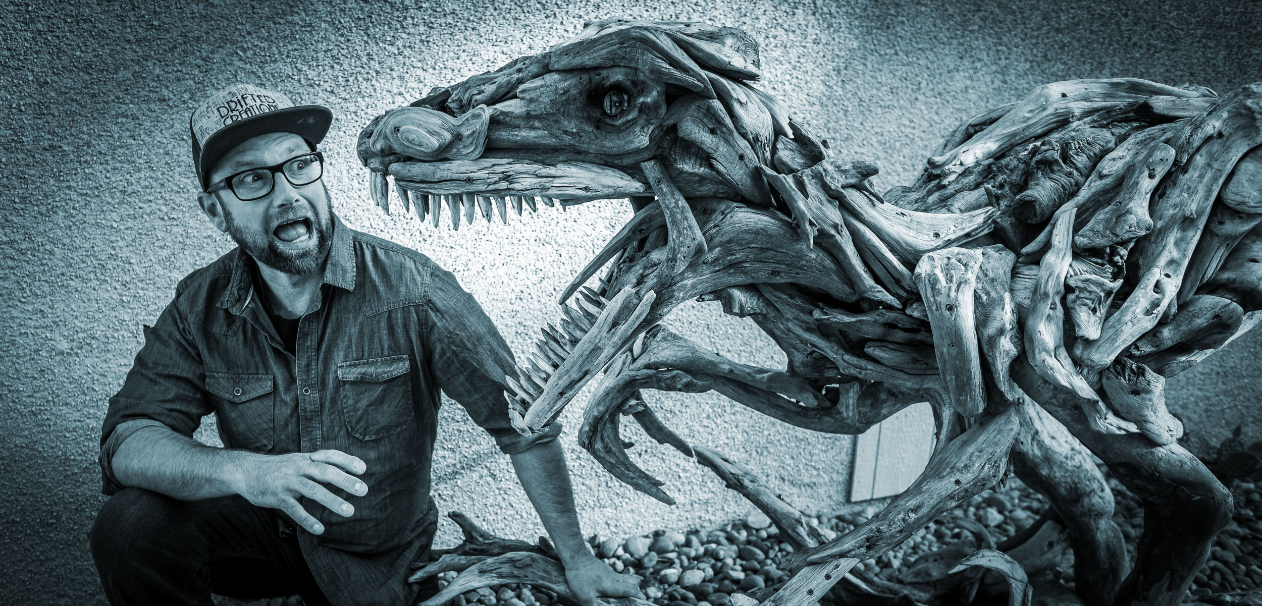 Driftwood artist Alex Witcombe poses with a Velociraptor sculpture