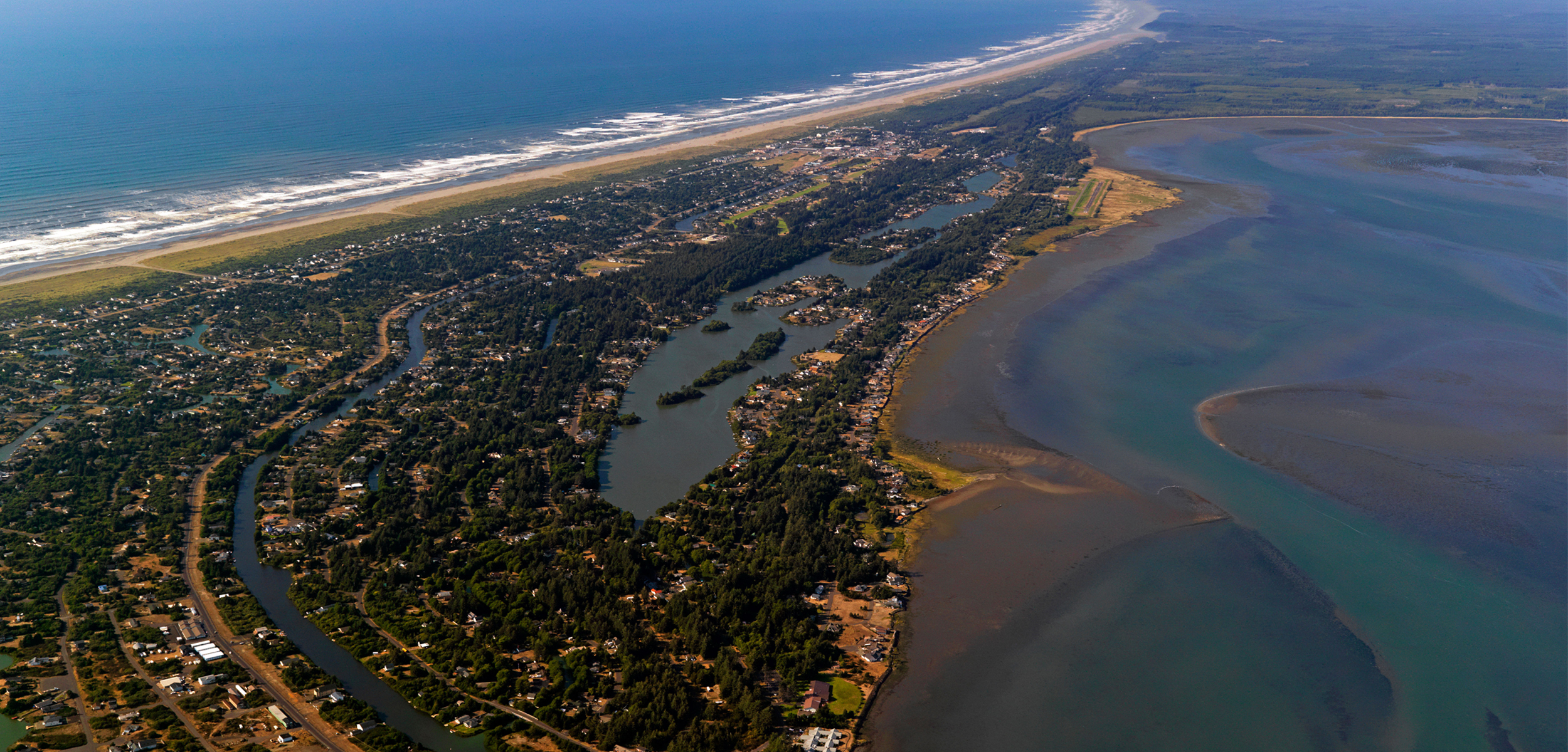 an aerial shot from a plae of the city of ocean shores sitting along the shore front.