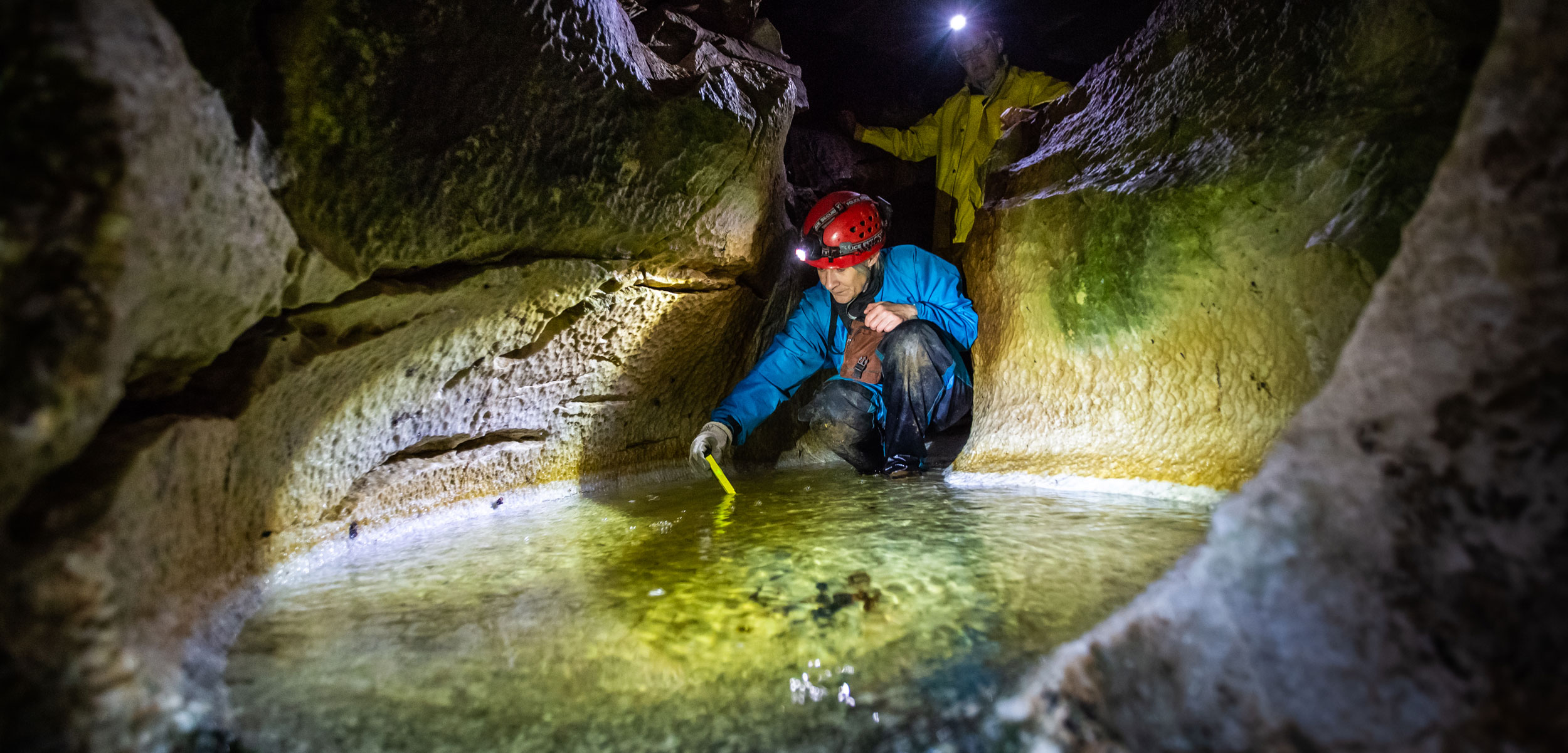 Scientist taking water sample from small pool in a cave.