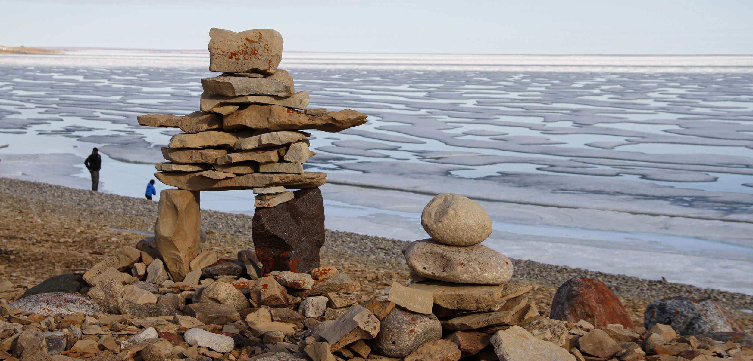 Inukshuk standing infront of a frozen sea