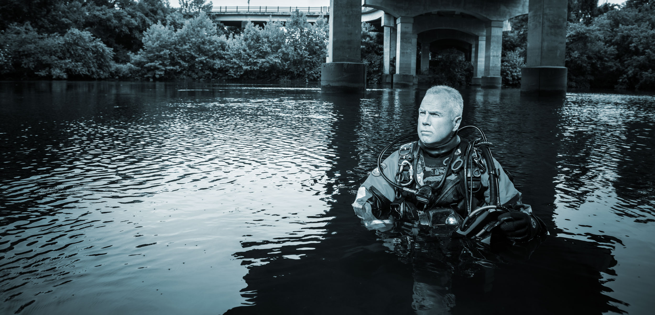 Underwater Investigator Mike Berry poses in a river under a bridge