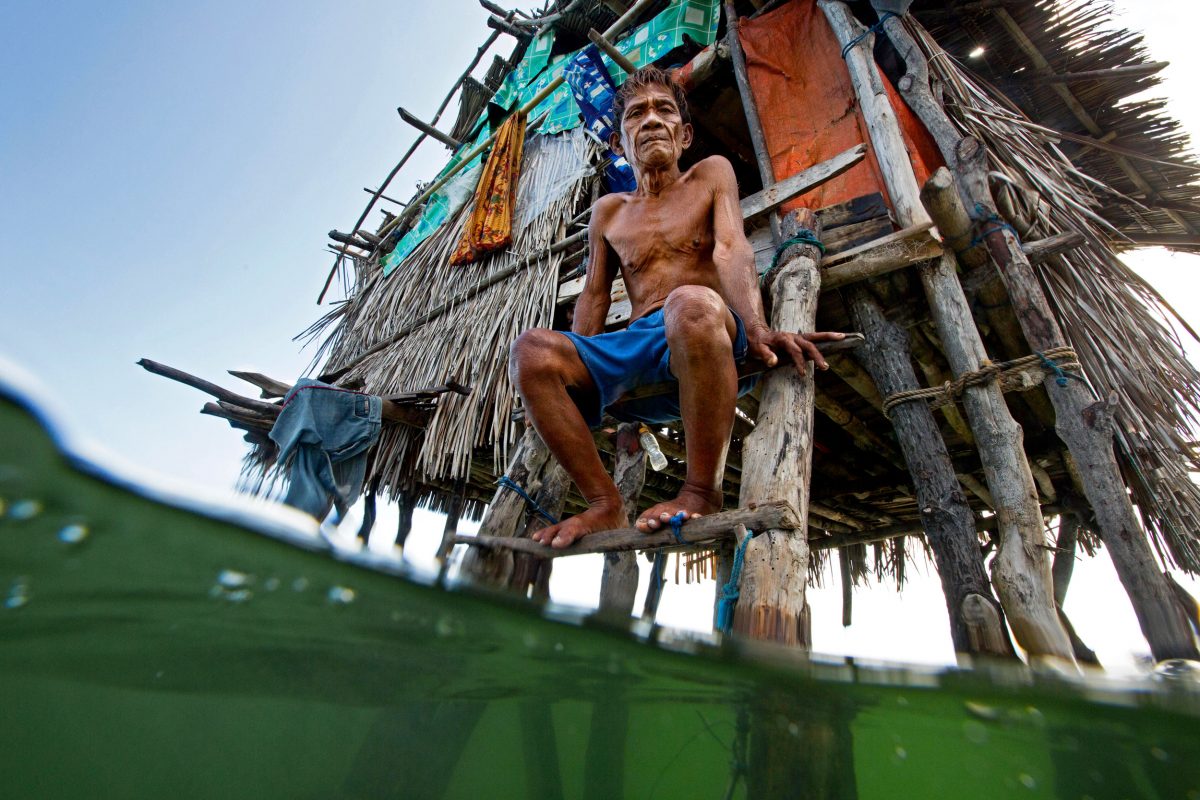 Bajau fisher sits in front of his home