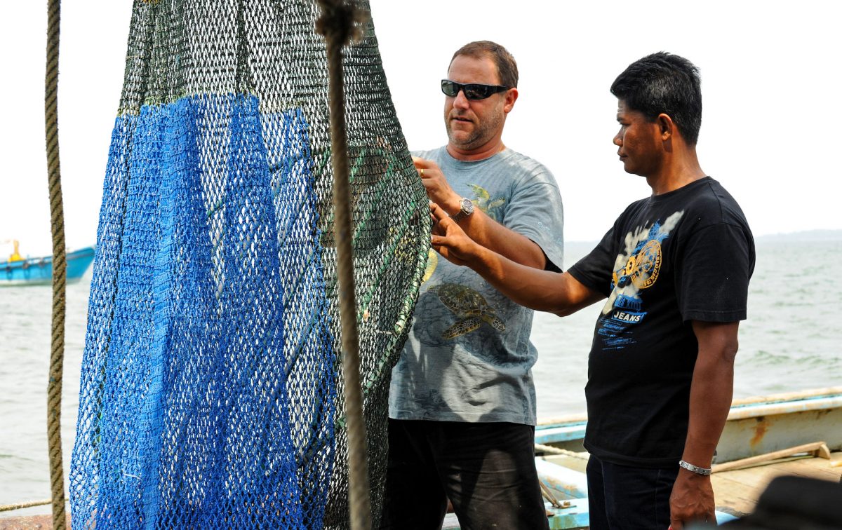 Nicolas Pilcher (left), from Malaysia’s Marine Research Foundation, shows a fisherman how to install a turtle excluder device