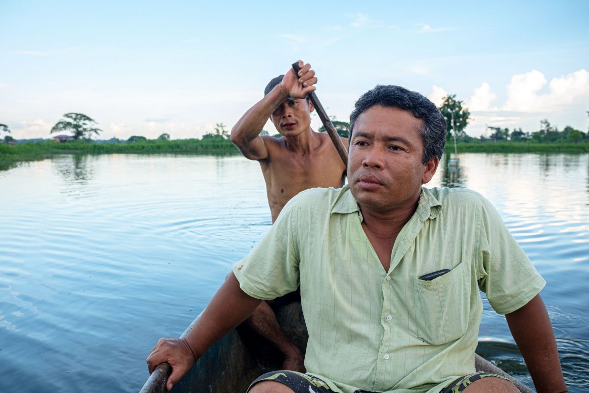 Ko Kyaw Sein Tun with one of his employees rowing boat around his fish pond