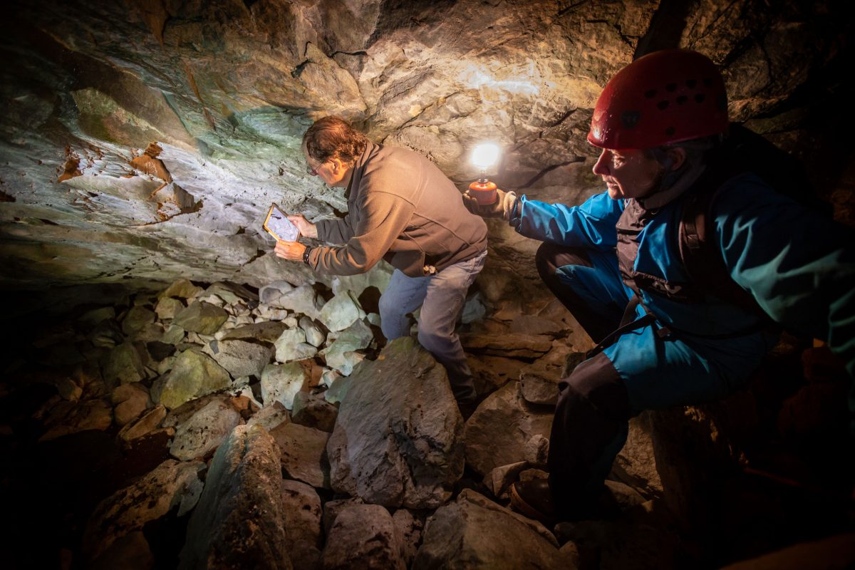 Researchers climb through a cave.