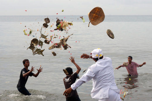 Devotees throw offerings into the ocean as part of a cleansing ritual known as Melasti. Photo by Made Nagi/epa/Corbis