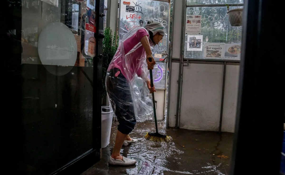 A shopkeeper clears floodwater from her store in Brooklyn, New York
