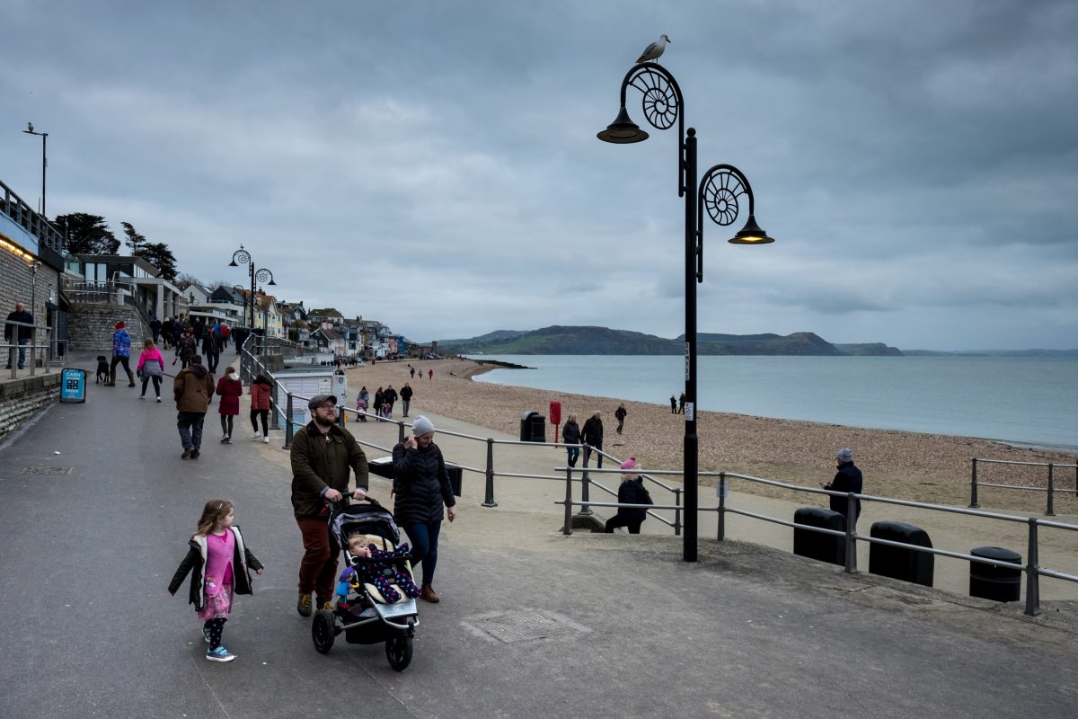 People walk along the seafront past streetlights shaped like ammonites in Lyme Regis. The town was the home of Mary Anning, and is one of the most productive areas of England’s Jurassic Coast.