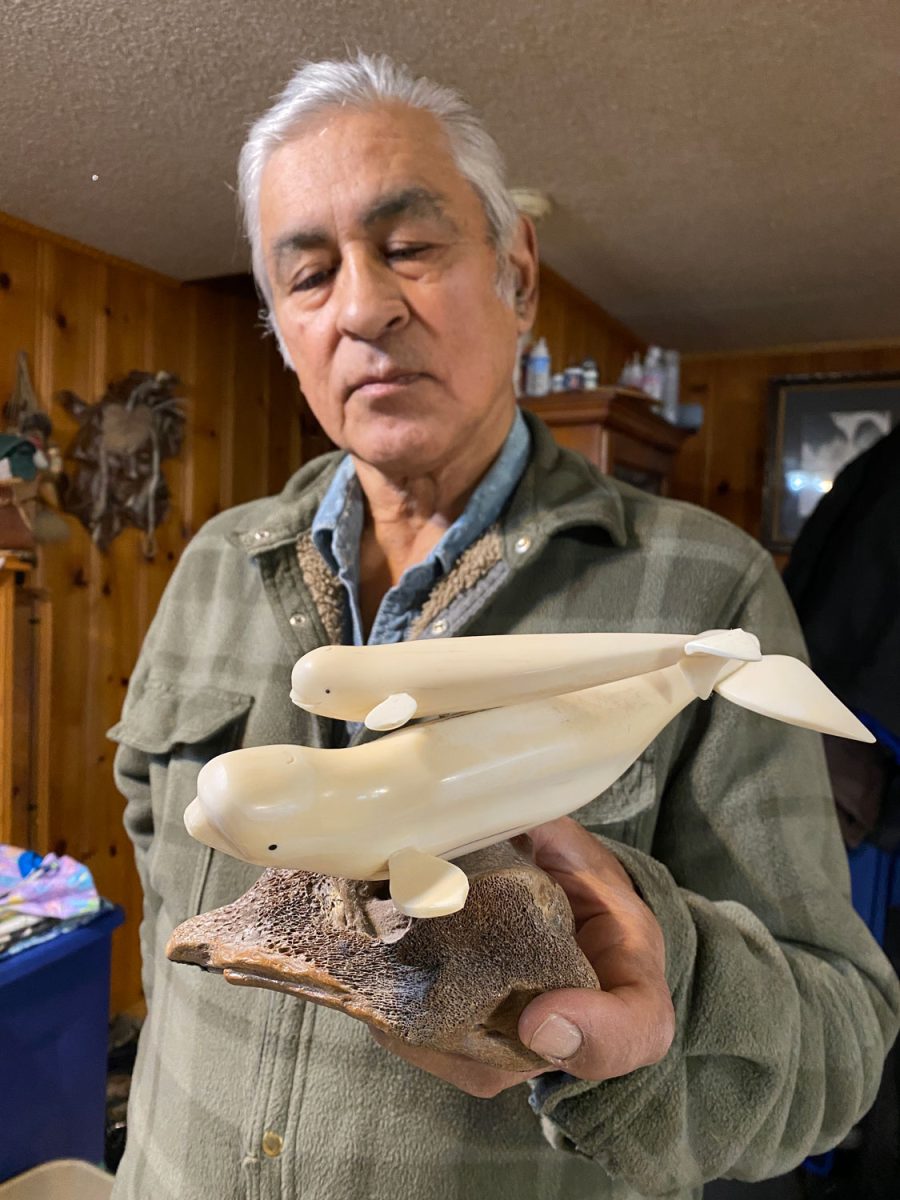 Roswell Schaeffer Sr. holds a sculpture of two beluga whales