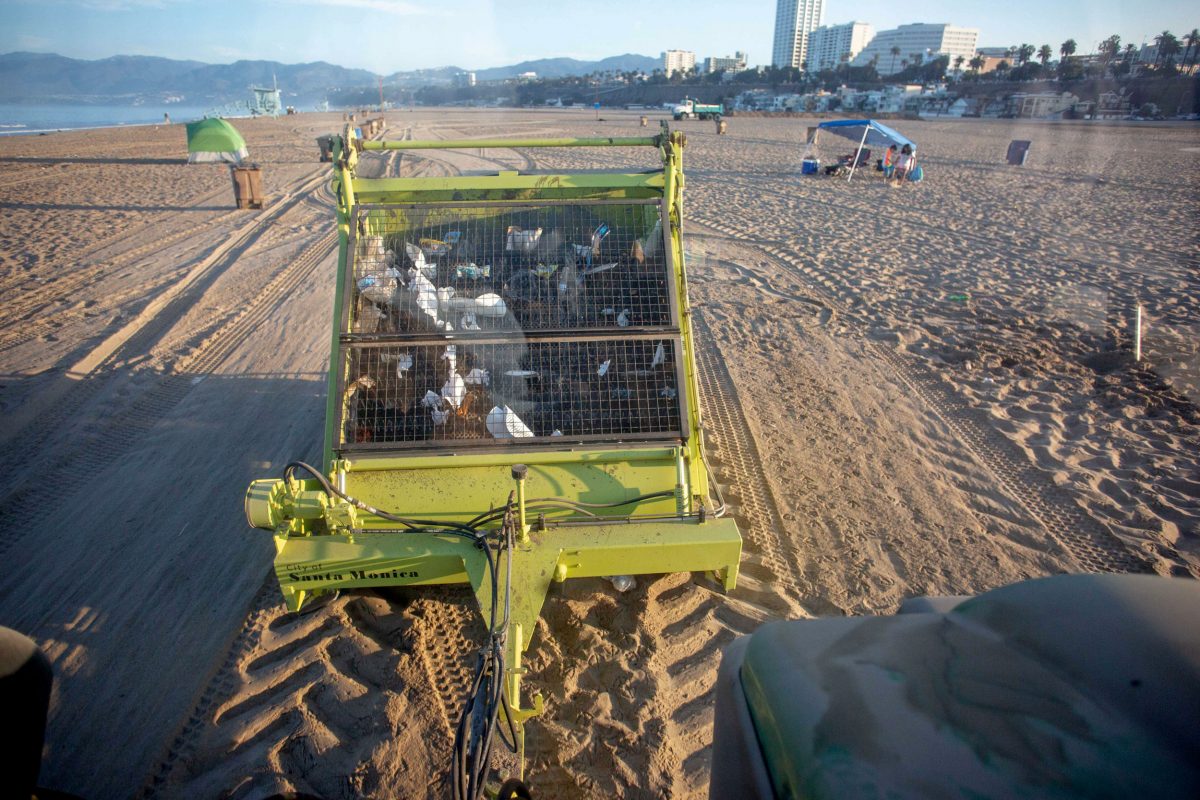 Garbage collecting trailer being towed along Santa Monica Beach by a tractor